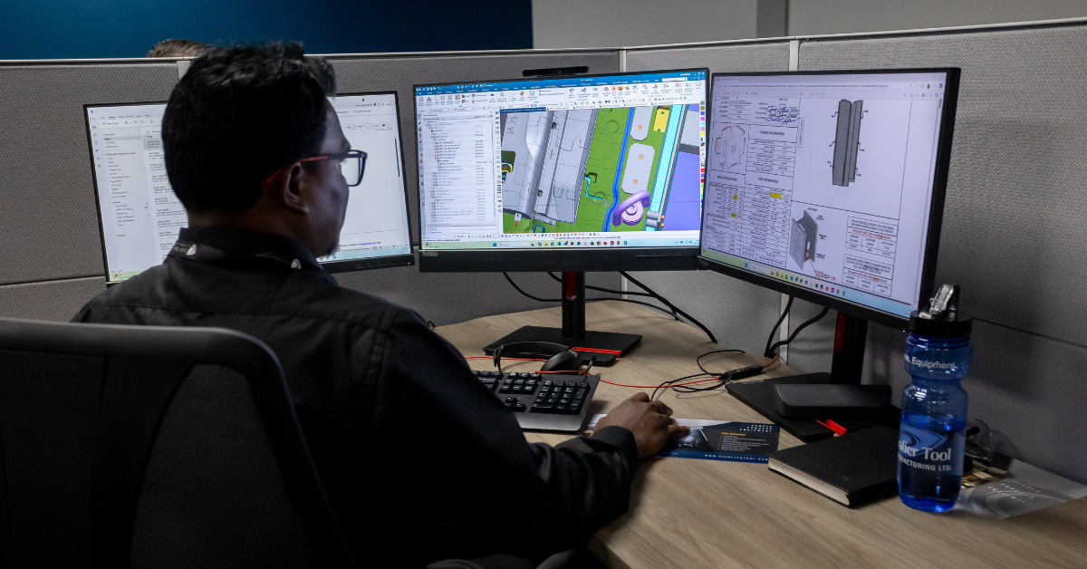 Vella, a team member from Cavalier Tool India sits at a work station in Cavalier Tool's World Headquarters in Windsor, Ontario, Canada. A design file is open on his main computer screen and a customer specification document on his other screen. He would normally be working on this file from his desk in India, thanks to our Global Tool and Mold Partnership he is able to see his design being manufactured in real time, offering valuable insight for his future work.